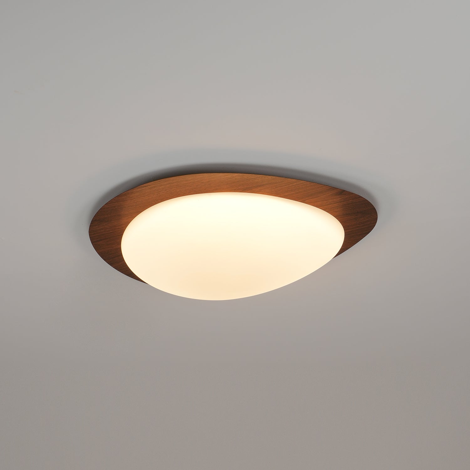 Loftslampe med rullestensinspireret silhuet, valnøddetræsfinish med synlig åretegning og varmt skær