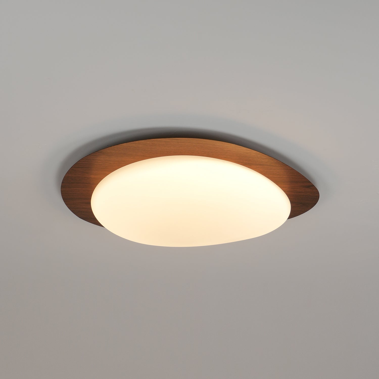Loftslampe med rullestensinspireret silhuet, valnøddetræsfinish med synlig åretegning og varmt skær